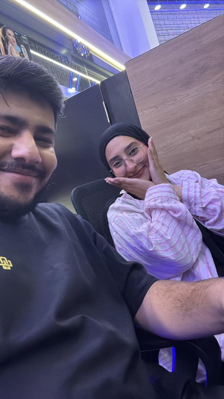 A selfie in a tech shop; behind me, Fatima poses with her chin in her hands, smiling.